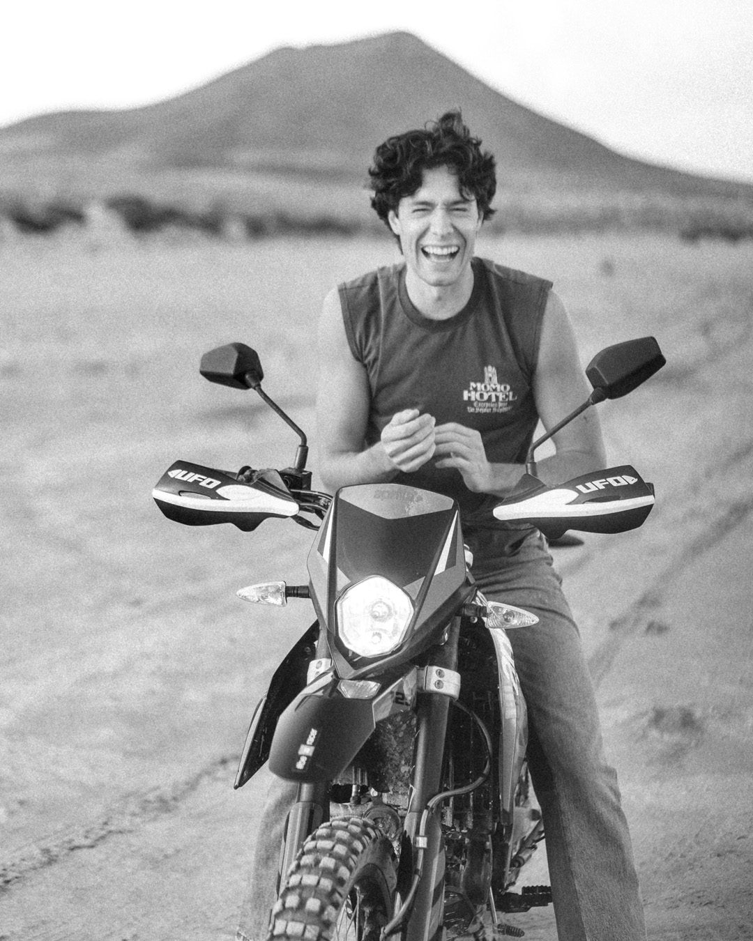 Gon Abril riendo sobre una moto, en blanco y negro